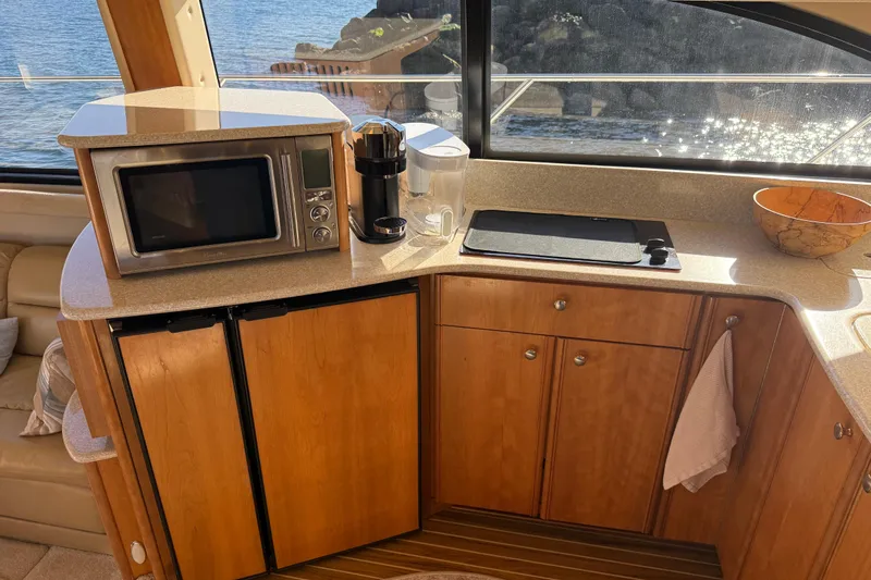  Yacht Photos Pics 2004 Meridian 411 Sedan kitchen with microwave, coffee maker, and wooden cabinets by a window.