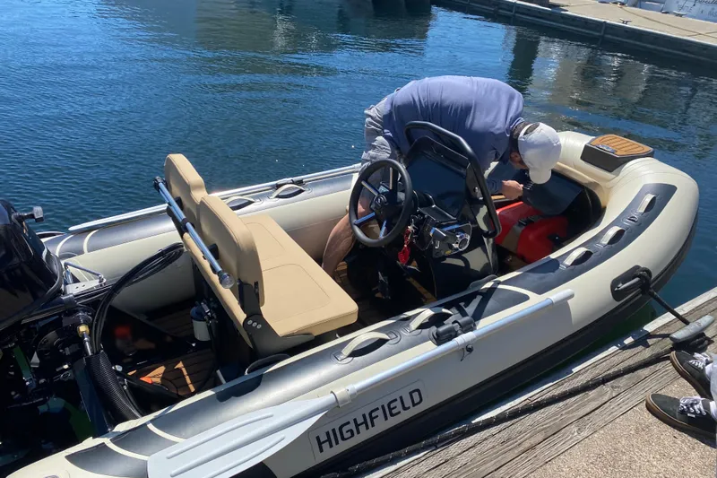  Yacht Photos Pics Man working on a Highfield inflatable boat at a dock, sunny day.