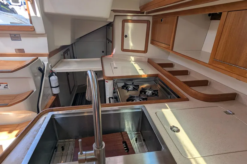 Alola Yacht Photos Pics Interior of 2003 Catalina 42 MkII yacht kitchen with stove, sink, and wooden cabinetry.