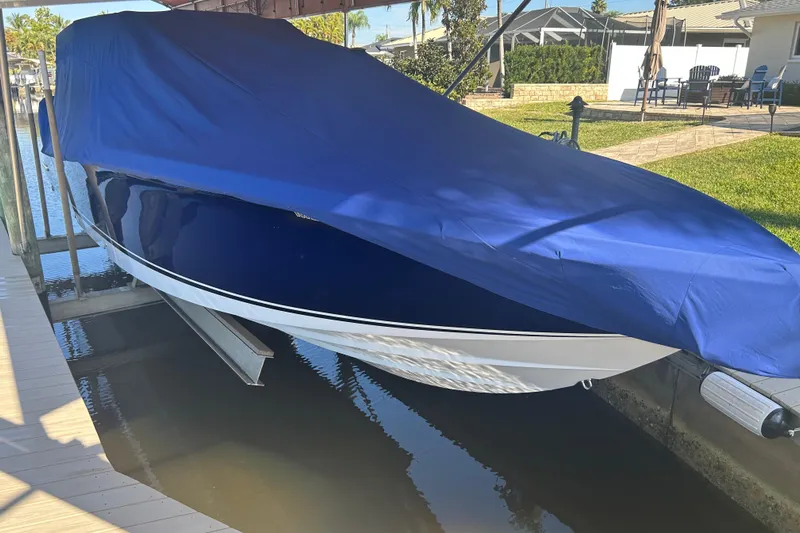  Yacht Photos Pics 2024 Nor-Tech 400 Supersport boat covered with a blue tarp, docked in a marina.