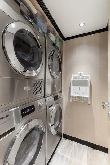 Rocket One Yacht Photos Pics Laundry room with stacked stainless steel washers and dryers on a 2022 Gulf Craft Majesty 120 yacht.