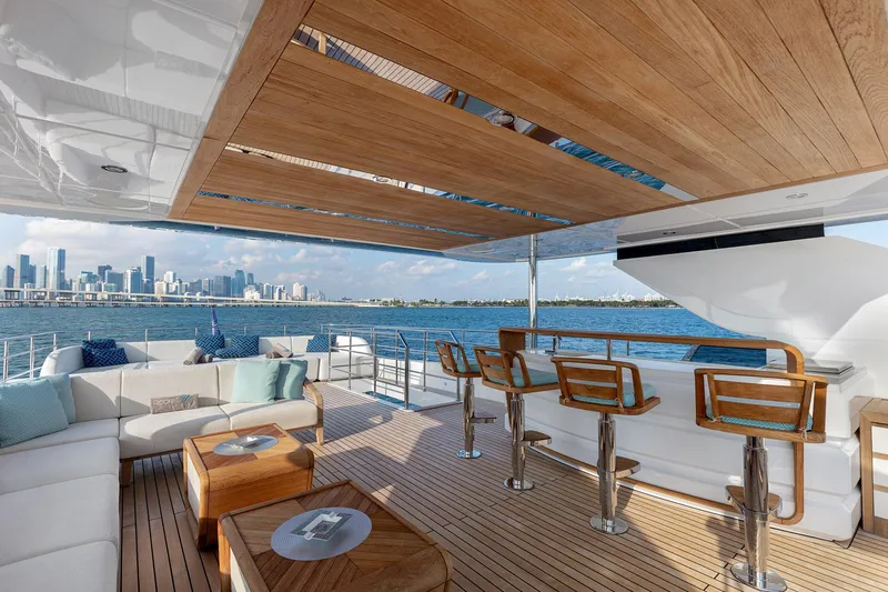 Rocket One Yacht Photos Pics Luxurious Gulf Craft Majesty 120 yacht deck with bar and seating, overlooking city skyline, 2022 model.