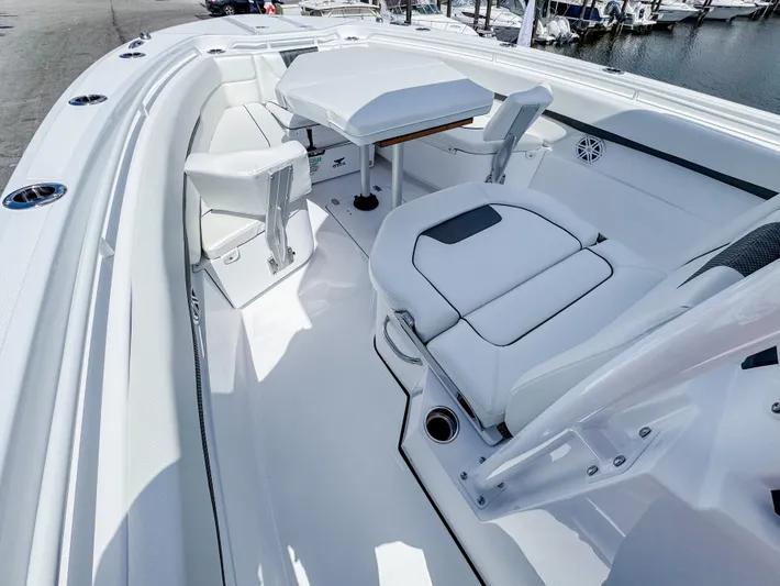  Yacht Photos Pics 2025 Wellcraft 302 Fisherman boat interior with white seating and table, docked at marina.