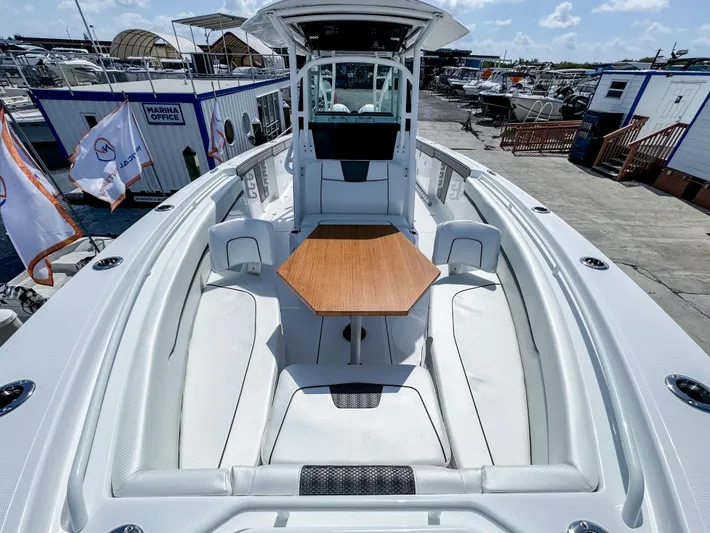  Yacht Photos Pics 2025 Wellcraft 302 Fisherman boat with spacious seating and wooden table, docked at marina.