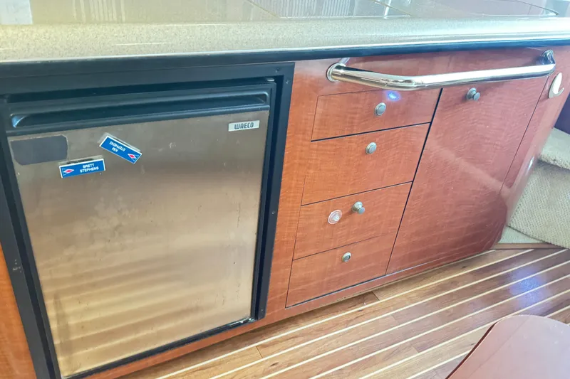  Yacht Photos Pics Interior of 2005 Sea Ray 340 Sundancer with wooden cabinetry and compact fridge.