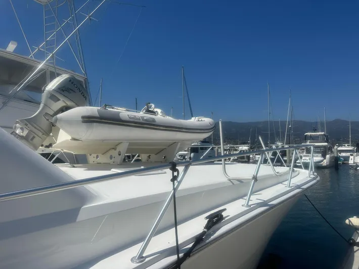 Gitana Yacht Photos Pics 2000 Viking Enclosed Flybridge yacht with dinghy, docked in a marina under clear blue skies.