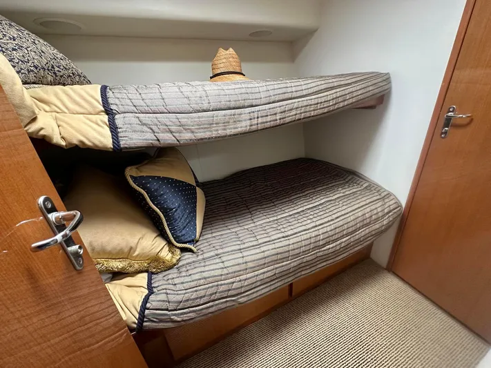 Gitana Yacht Photos Pics Bunk beds in 2000 Viking Enclosed Flybridge cabin with cozy bedding and a straw hat.