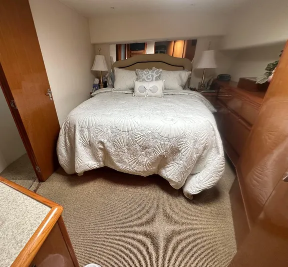 Gitana Yacht Photos Pics Cozy bedroom in 2000 Viking Enclosed Flybridge yacht with elegant bedding and wooden furnishings.