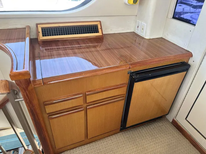 Gitana Yacht Photos Pics Wooden cabinetry and mini fridge inside 2000 Viking Enclosed Flybridge yacht interior.
