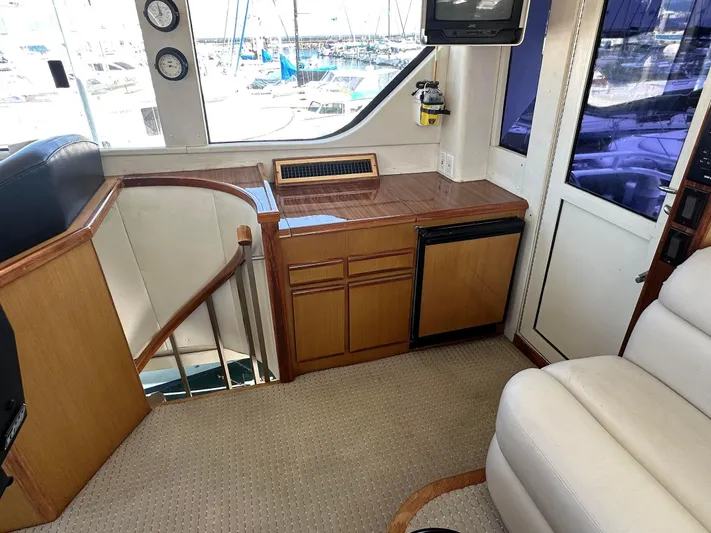 Gitana Yacht Photos Pics 2000 Viking Enclosed Flybridge interior with wood cabinetry, mini fridge, and nautical instruments.