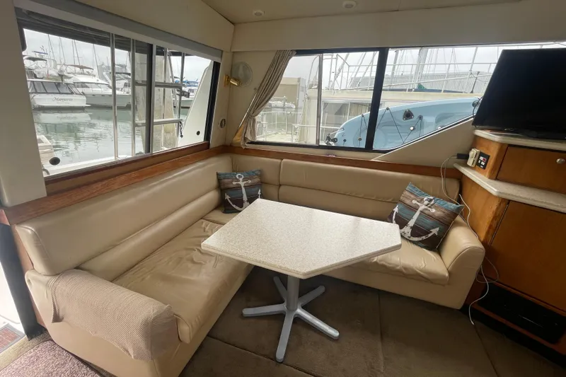  Yacht Photos Pics 1999 Bayliner 3988 Motoryacht interior with beige seating, table, and marina view.