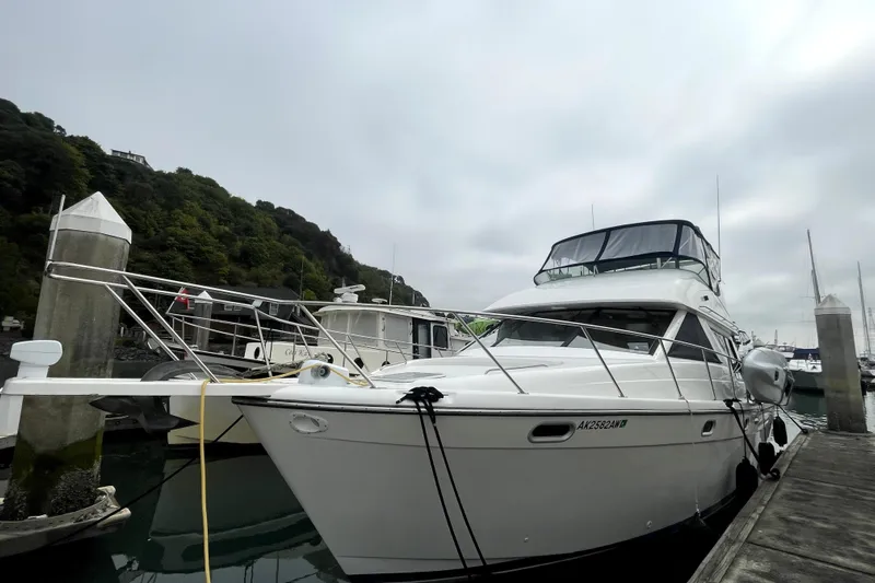  Yacht Photos Pics 1999 Bayliner 3988 Motoryacht docked at a marina with lush green hills.