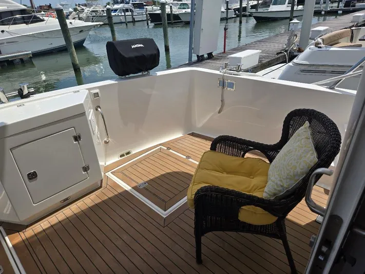 Chinook Yacht Photos Pics Outdoor seating area on 2010 American Tug 49 Limited yacht, featuring wicker chair and marina view.