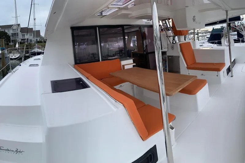 Freckled Parrot Yacht Photos Pics 2015 Fountaine Pajot Helia 44 catamaran with orange seating and wooden table on deck.