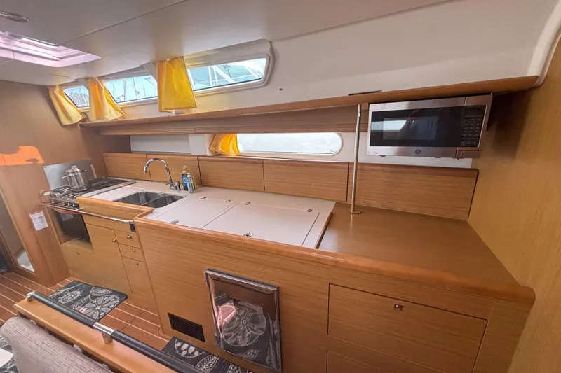  Yacht Photos Pics Interior of 2009 Jeanneau Sun Odyssey 44i yacht, featuring a modern kitchen with wood finish.