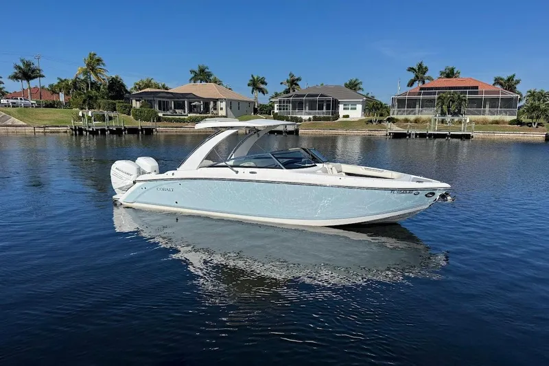  Yacht Photos Pics 2018 Cobalt 30SC boat on calm water, with waterfront homes and palm trees in the background.