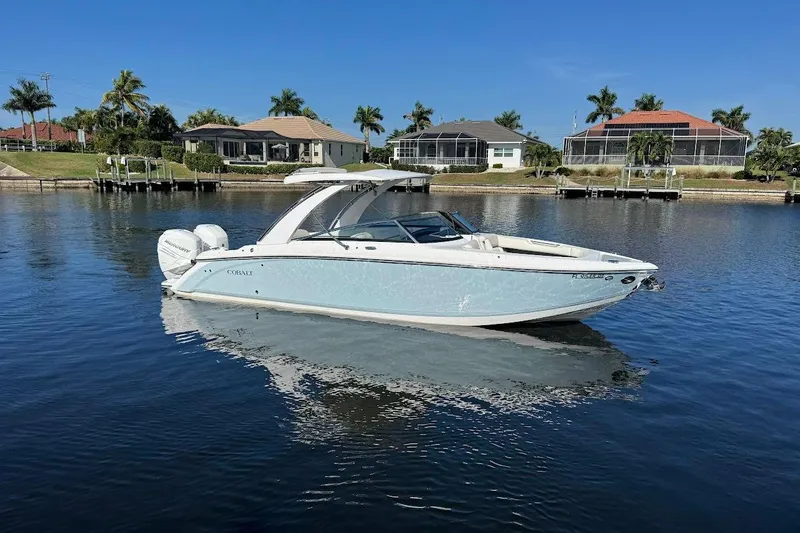  Yacht Photos Pics 2018 Cobalt 30SC boat on calm water, with waterfront homes and palm trees in the background.