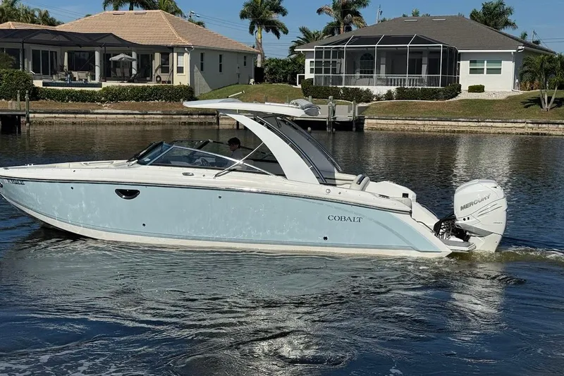  Yacht Photos Pics 2018 Cobalt 30SC boat cruising on a calm waterway near waterfront homes.