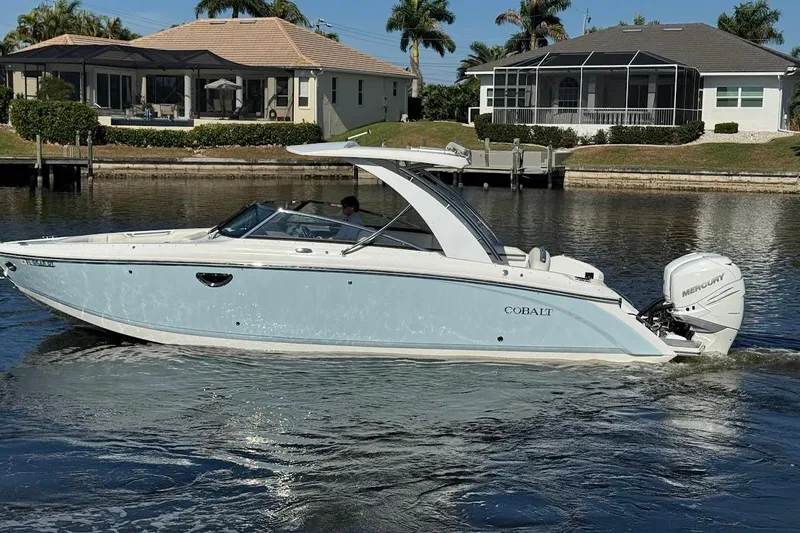  Yacht Photos Pics 2018 Cobalt 30SC boat cruising on a calm waterway near waterfront homes.