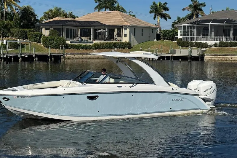  Yacht Photos Pics 2018 Cobalt 30SC boat cruising on a sunny waterfront with houses in the background.