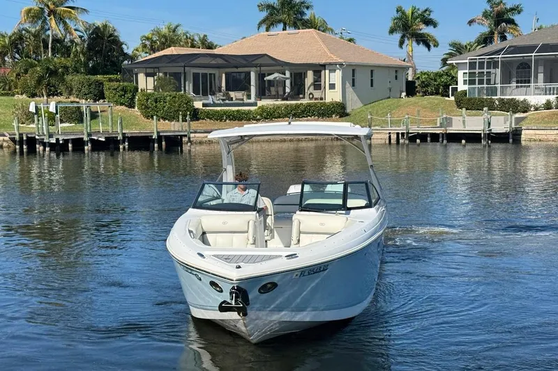  Yacht Photos Pics 2018 Cobalt 30SC boat cruising on a sunny waterfront with houses and palm trees.