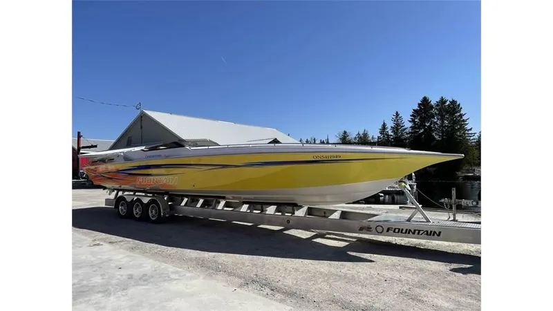 Yacht Photos Pics Yellow 2006 Fountain 42 speedboat on trailer, parked outdoors under clear blue sky.