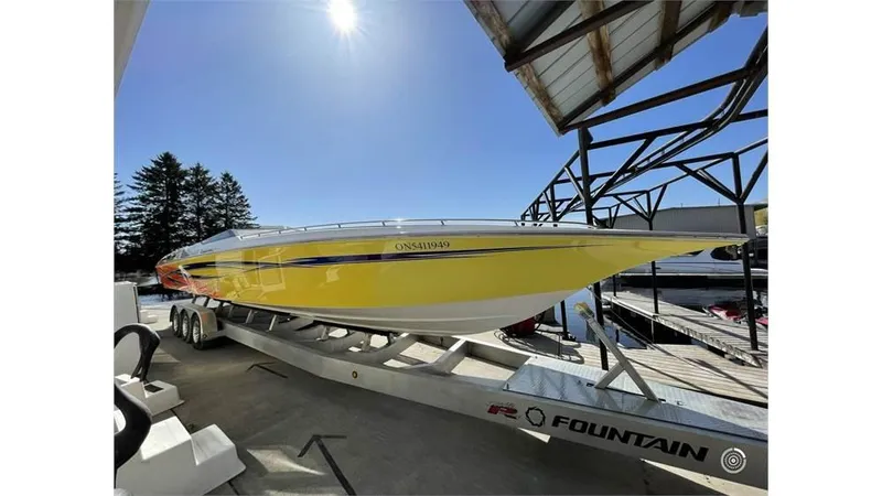  Yacht Photos Pics Yellow 2006 Fountain 42 speedboat on trailer under clear blue sky.