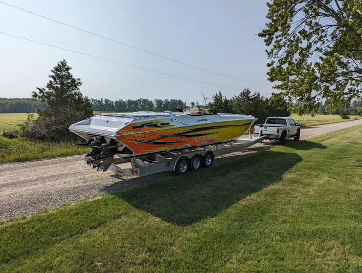  Yacht Photos Pics 2006 Fountain 42 speedboat on trailer, vibrant orange and yellow design, parked on rural road.