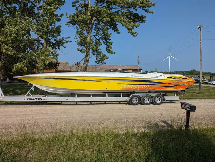  Yacht Photos Pics 2006 Fountain 42 speedboat on trailer, vibrant yellow and orange design, parked on a rural road.