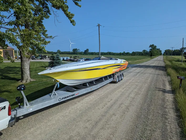  Yacht Photos Pics Yellow 2006 Fountain 42 speedboat on trailer, parked on rural dirt road.