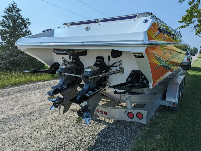  Yacht Photos Pics 2006 Fountain 42 boat on trailer, dual engines, vibrant orange design, parked on gravel road.
