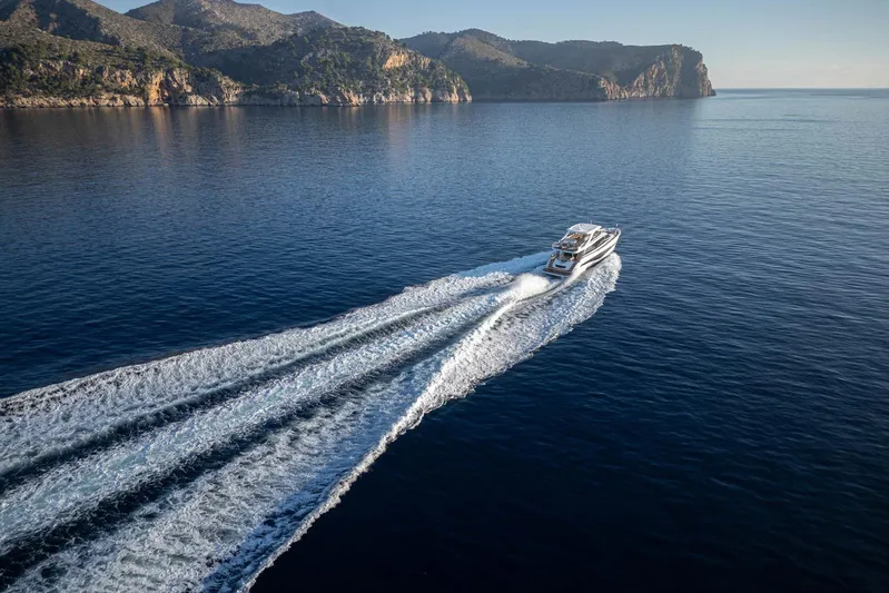  Yacht Photos Pics 2024 Princess Y80 yacht cruising on serene blue waters near rocky coastline.