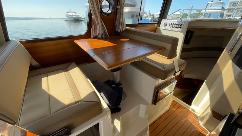  Yacht Photos Pics 2022 Ranger Tugs R-25 interior with dining area, wooden table, and waterfront view.