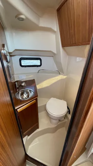  Yacht Photos Pics 2022 Ranger Tugs R-25 boat bathroom with sink, toilet, and wooden cabinetry.