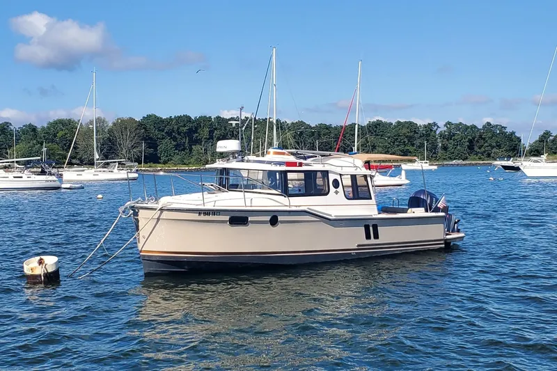 Tusen Takk Yacht Photos Pics 2024 Ranger Tugs R-27 boat anchored in a scenic harbor with sailboats.