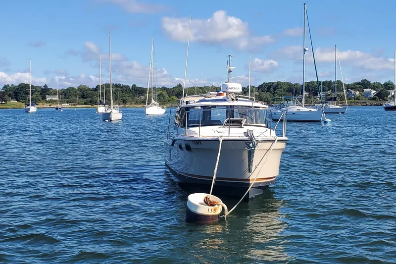 Tusen Takk Yacht Photos Pics 2024 Ranger Tugs R-27 boat moored in a scenic harbor with sailboats.