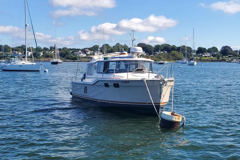 Tusen Takk Yacht Photos Pics 2024 Ranger Tugs R-27 boat anchored in a scenic harbor with sailboats.