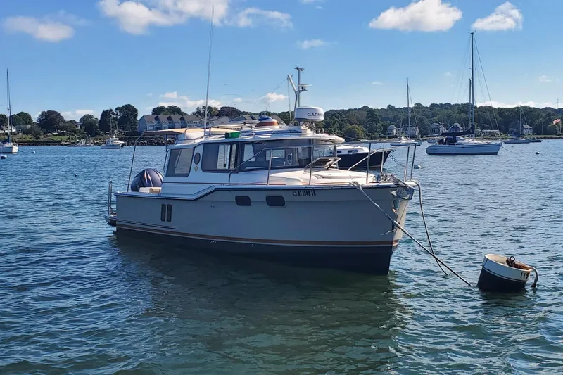 Tusen Takk Yacht Photos Pics 2024 Ranger Tugs R-27 boat moored in a scenic harbor with sailboats.
