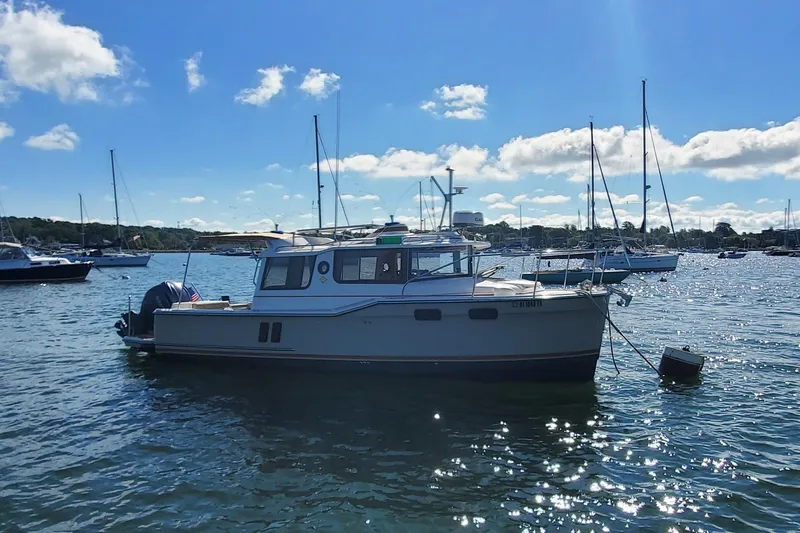 Tusen Takk Yacht Photos Pics 2024 Ranger Tugs R-27 boat anchored in a sunny harbor with other vessels.