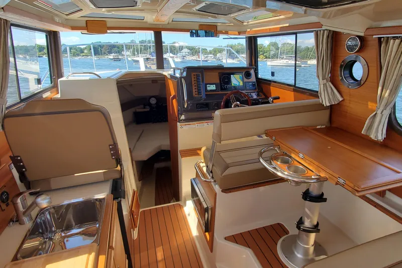 Tusen Takk Yacht Photos Pics 2024 Ranger Tugs R-27 interior with wood accents, navigation system, and seating area.