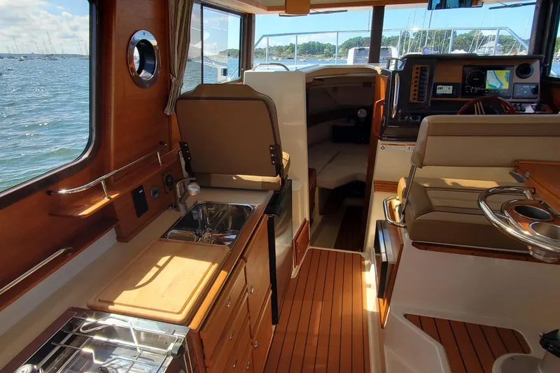 Tusen Takk Yacht Photos Pics 2024 Ranger Tugs R-27 interior with wood finish, kitchenette, and helm, overlooking water.