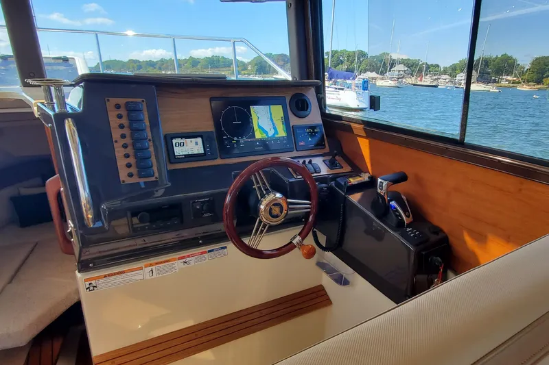 Tusen Takk Yacht Photos Pics 2024 Ranger Tugs R-27 helm with navigation screens and steering wheel, overlooking marina.