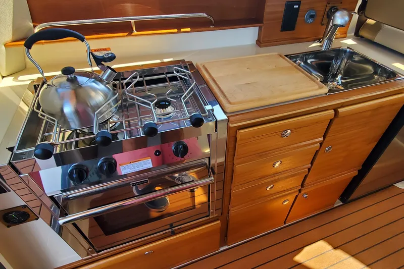 Tusen Takk Yacht Photos Pics 2024 Ranger Tugs R-27 galley with stove, sink, and wooden cabinetry.