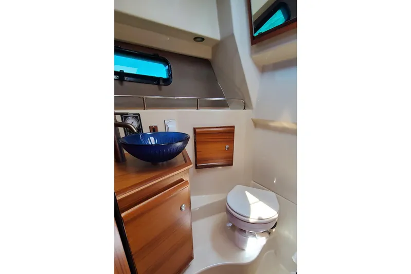 Tusen Takk Yacht Photos Pics 2024 Ranger Tugs R-27 bathroom with modern sink and toilet, featuring wood cabinetry.