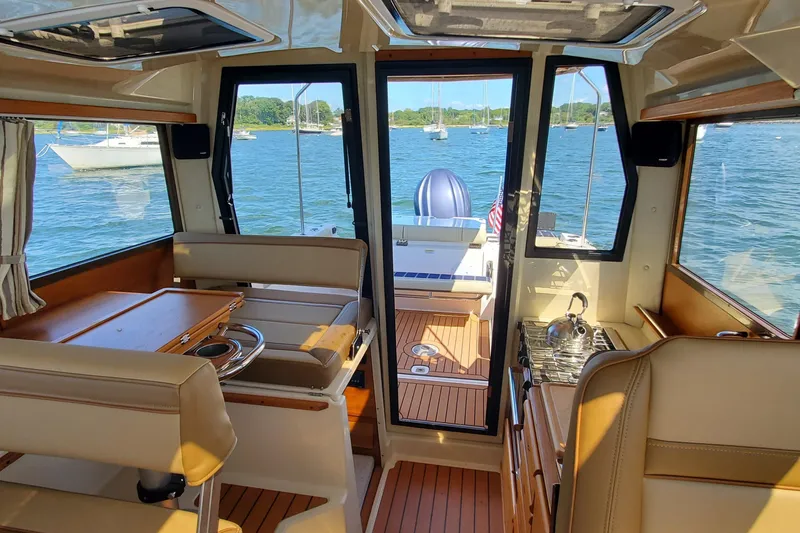 Tusen Takk Yacht Photos Pics Interior view of 2024 Ranger Tugs R-27 boat with seating and kitchenette, overlooking water.