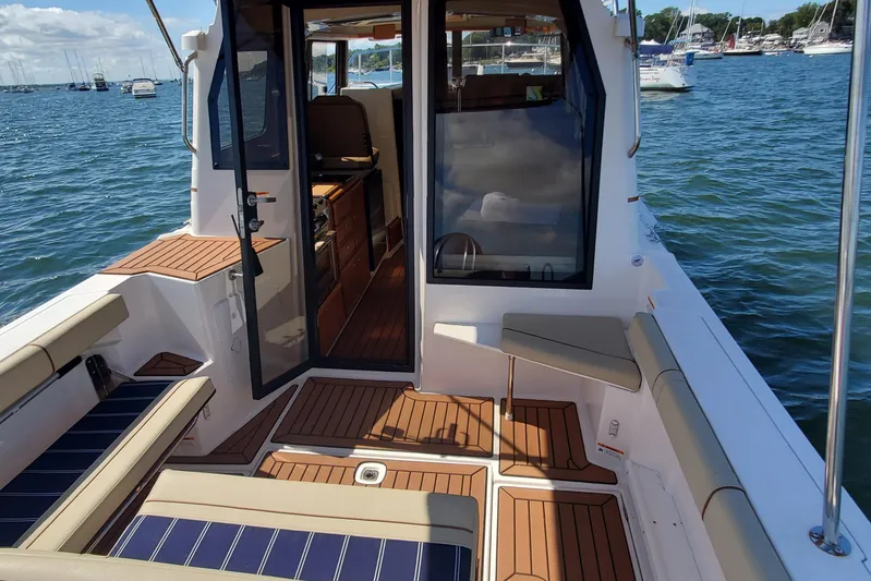 Tusen Takk Yacht Photos Pics 2024 Ranger Tugs R-27 boat interior with seating, open door, and scenic water view.