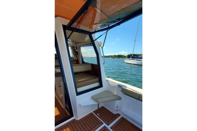 Tusen Takk Yacht Photos Pics 2024 Ranger Tugs R-27 interior with open window, overlooking serene waters and sailboats.