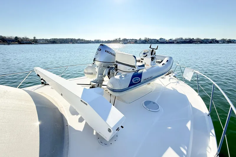 Steel Dreamin Yacht Photos Pics 2004 Silverton 48 Convertible yacht with dinghy on deck, cruising on calm waters.