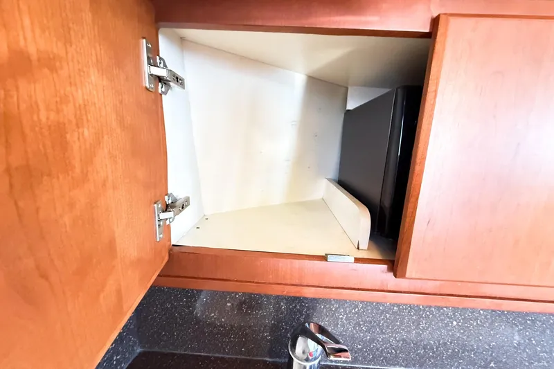 Steel Dreamin Yacht Photos Pics Open wooden cabinet on 2004 Silverton 48 Convertible yacht, revealing interior storage space.