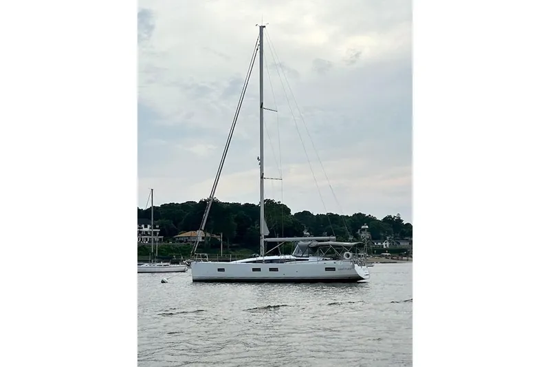  Yacht Photos Pics 2020 Jeanneau 54 sailboat anchored on calm water with scenic background.